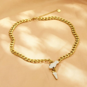 Detail of gold Cuban chain necklace with a rhinestone-encrusted snake pendant on silk