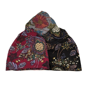 Three bohemian style knit beanies in burgundy, black, and grey with floral patterns