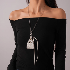 Détail du pendentif sac à main en strass argenté sur une longue chaîne de pull