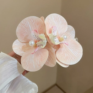 Detailed close-up of double fabric orchid hair clip with faux pearl centers in soft pink