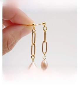 Detail view of gold chain drop earrings with elegant light pink teardrop pearls