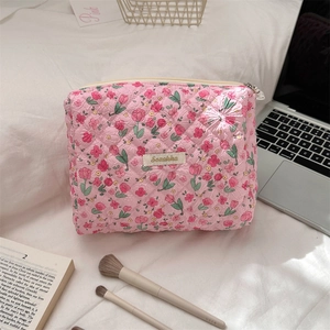 Detailed view of pink quilted tulip floral makeup bag on a soft fabric background