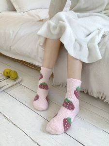 Close-up of pink coral fleece thermal mid-calf socks with purple strawberry pattern