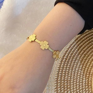 Bracelet tendance à fleurs dorées et papillon avec chaîne serpent porté sur un poignet