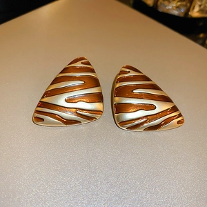 Détail de boucles d'oreilles triangulaires plaquées or avec motif zébré en émail brun