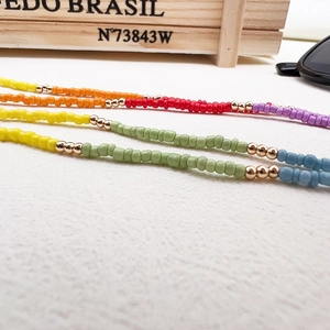 Macro shot of colorful glass seed bead necklace with gold spacer beads on white surface