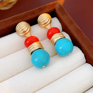 Macro detail of vintage gold earrings with red beads and turquoise stone in a jewelry box