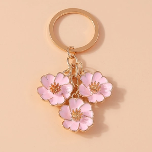 Detailed close-up of pink enamel flower charms on a golden metal keychain link