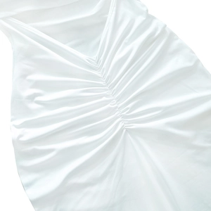 Detailed view of the elegant ruched pleated design on a white off-shoulder dress fabric