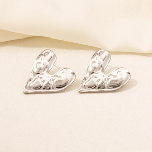 Macro view of heart-shaped earrings with hammered silver texture and 18K plating