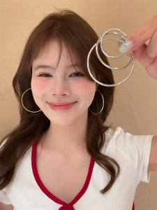 Three sizes of silver hoop earrings shown on a hand for scale comparison