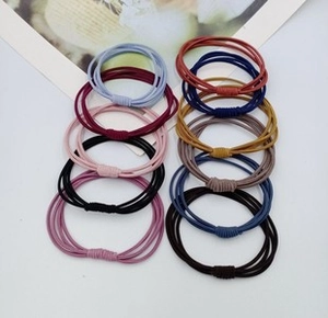 Detail view of ten colorful high-elasticity hair bands arranged neatly on a white desk