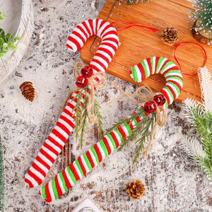 Christmas candy cane hanging ornaments with bells and bows on snow wood background