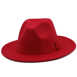 Detail of red fedora hat featuring a matching satin ribbon and wool felt texture