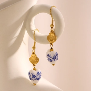 Close-up of gold 18k plated blue and white porcelain heart and teardrop earrings
