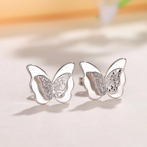 Macro view of silver double-layered butterfly studs with delicate hammered texture