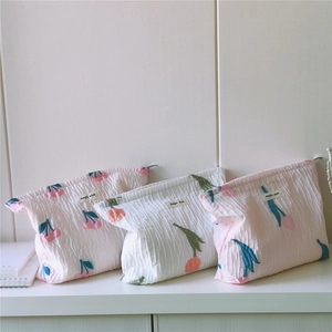 Détail de trois trousses de maquillage en tissu plissé avec motifs tulipes et cerises