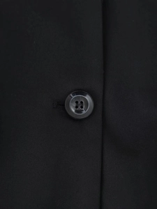 Détail macro du tissu sergé de haute qualité et du bouton noir à quatre trous sur le blazer
