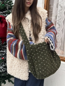 Winter plush green heart crossbody bag with white dots shown in a cozy holiday scene