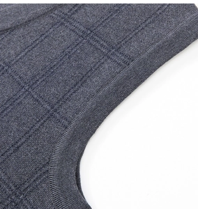 Macro shot of dark grey-blue knit vest featuring ribbed edges and textured plaid pattern