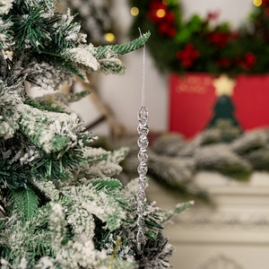 Close-up of spiral acrylic icicle ornament hanging on a snowy Christmas tree branch