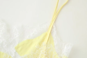 Detail of yellow camisole with delicate white lace trim and adjustable spaghetti straps