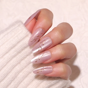 Cat eye almond press-on nails with golden leaf patterns on pinkish-purple base