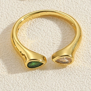Makro-Detail eines Goldbypas-Rings mit birnenförmigem smaragdgrünem und klarem Zirkonia