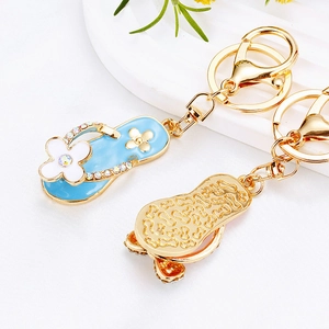 Detail of flip-flop keychains featuring blue enamel flower design and gold metal texture