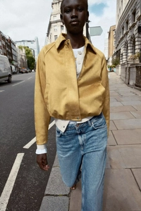 Detail of yellow faux suede cropped jacket with metal zipper and turn-down collar