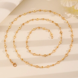 Close-up of golden Y-shaped crystal pearl necklace featuring heart links and lobster clasp