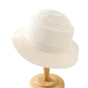 Minimalist beige crochet knit sun hat with textured pattern on a wooden stand