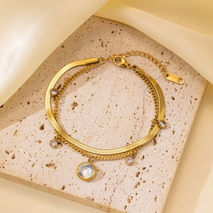 Detalle de una cadena doble de acero dorado con cinco circonitas redondas brillantes