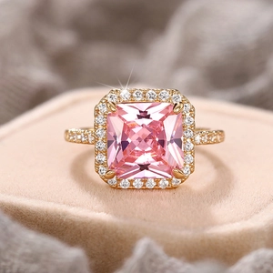 Macro shot of gold ring with square pink stone and diamond accents on velvet