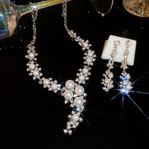 Detailed view of elegant silver necklace and drop earrings with pearls and crystals