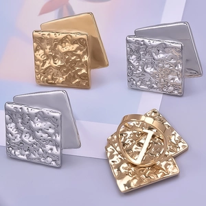Macro detail of gold and silver square rings with irregular crumpled texture finish