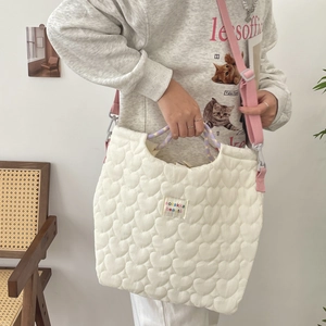 Detail van gewatteerde canvas tas met hartpatroon, paars handvat en roze verstelbare schouderriem