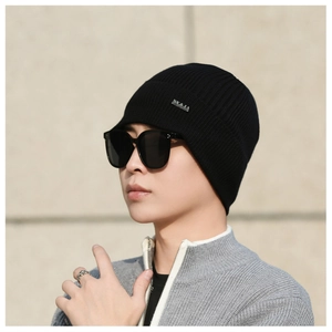 Close-up of black ribbed knit beanie with silver metal logo plaque for winter warmth