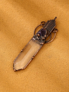 Detailed close-up of a vintage bronze pendant with white quartz and raw amethyst stone