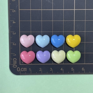 Macro shot of 1cm colorful resin heart charms on scale mat for DIY jewelry making