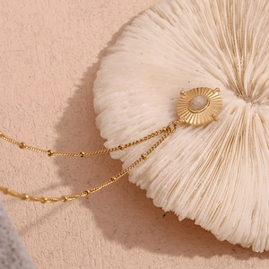 Detailed macro view of 18K gold plated oval necklace with white crystal on coral base