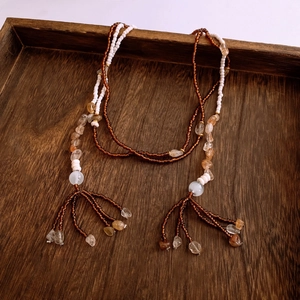 Macro detail of irregular glass beads and natural stone tassels on a wooden tray