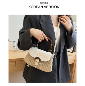 Detail view of woven straw bag featuring floral embroidery and natural bamboo handle