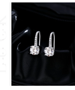 Macro detail of sparkling 1-carat moissanite earrings with silver hooks and small diamonds