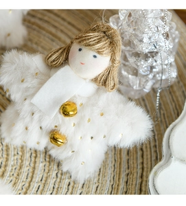 Close-up of white plush Christmas angel with gold polka dots and bells on woven background