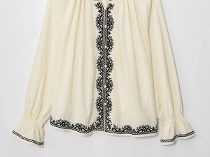 Détail d'une chemise vintage en coton et lin avec broderie noire et poignets à volants