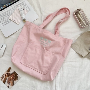 Sac cabas en toile rose avec broderie de nœuds bleu clair et poches sur fond blanc