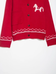 Détail du cardigan rouge en maille avec broderie cheval blanc et motif géométrique