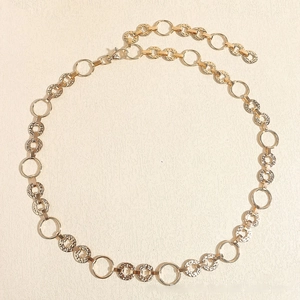 Detail of golden metal chain belt with hammered discs and adjustable lobster clasp