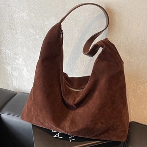 Brown suede hobo bag for women, large capacity shoulder tote leaning against a grey wall